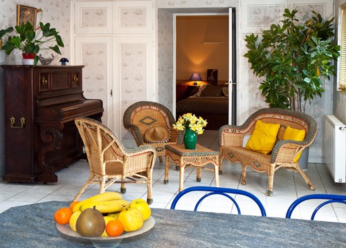 Salon du gîte Marjorie, avec fauteuils en rotin et piano droit